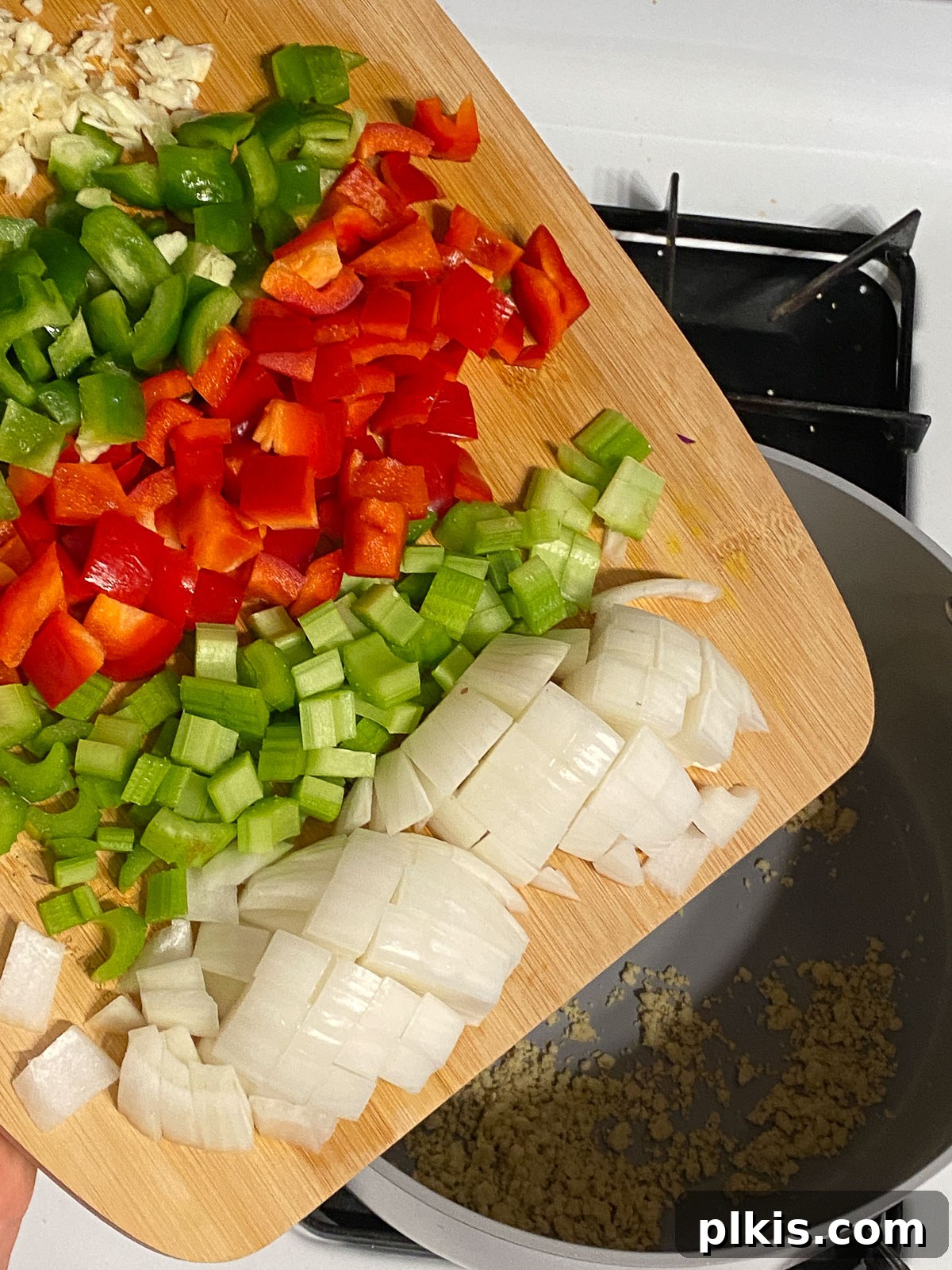 Hearty Plant-Based Gumbo 6 process shot of diced vegetables being poured into the pan with the roux