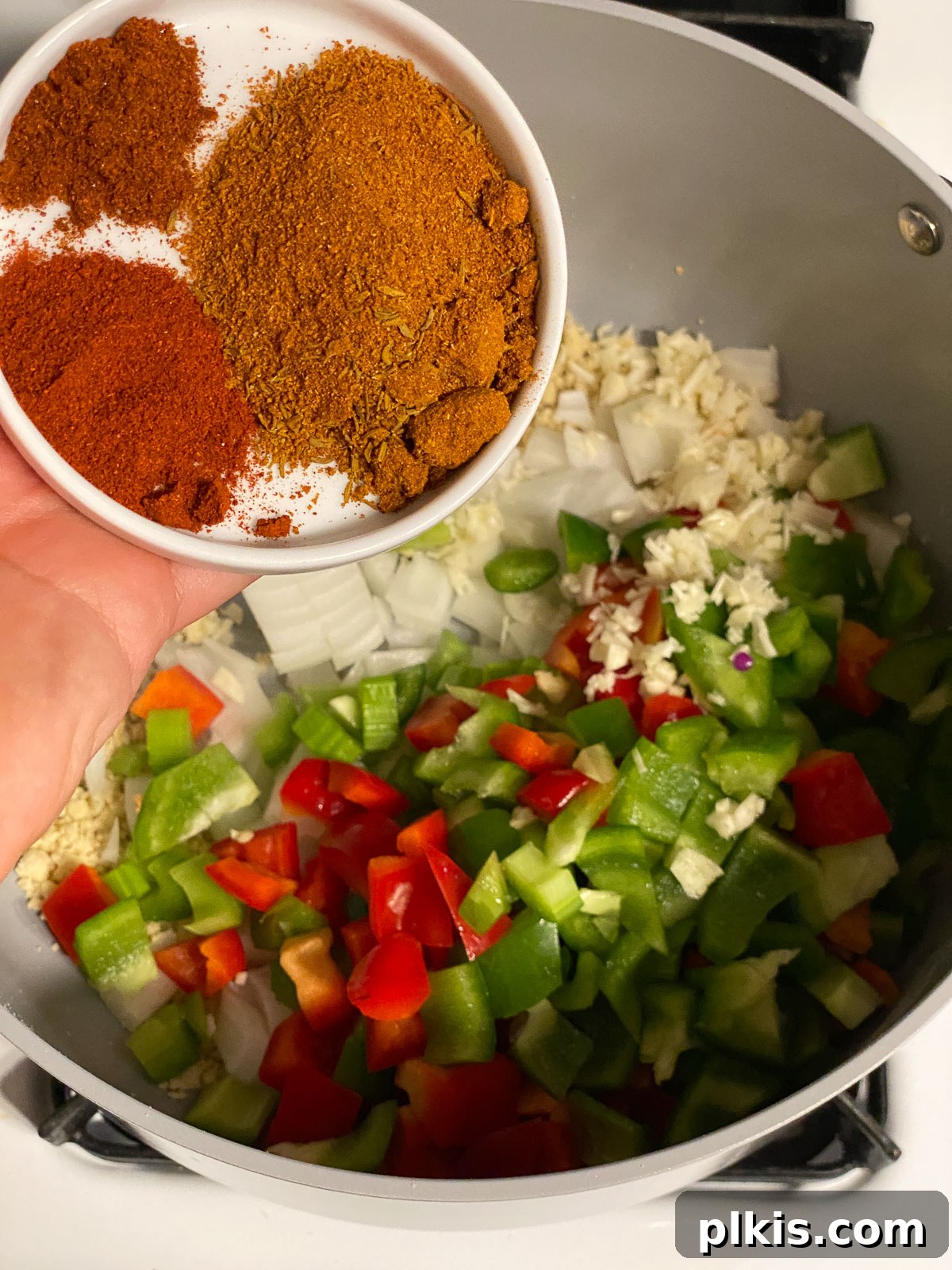 Hearty Plant-Based Gumbo 7 process shot of various spices being added into the pan with vegetables and roux