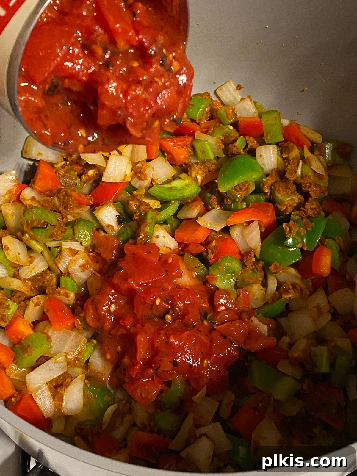 Hearty Plant-Based Gumbo 9 process shot of canned fire-roasted tomatoes being added into the pan