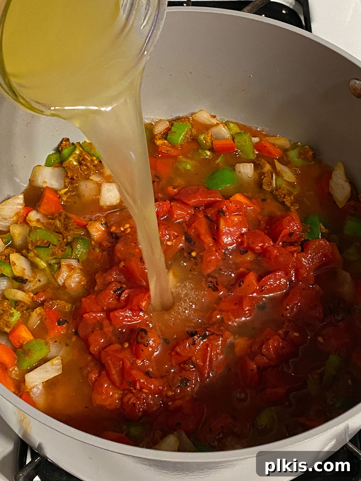 Hearty Plant-Based Gumbo 10 process shot of vegetable broth being added to the simmering mixture in the pan