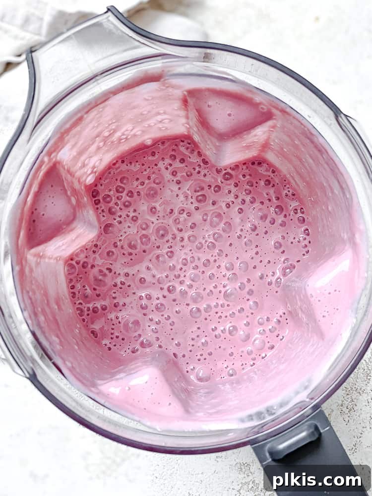 Effortless Raspberry Refresh 5 Process shot showing the raspberry smoothie ingredients fully blended and creamy inside the blender.