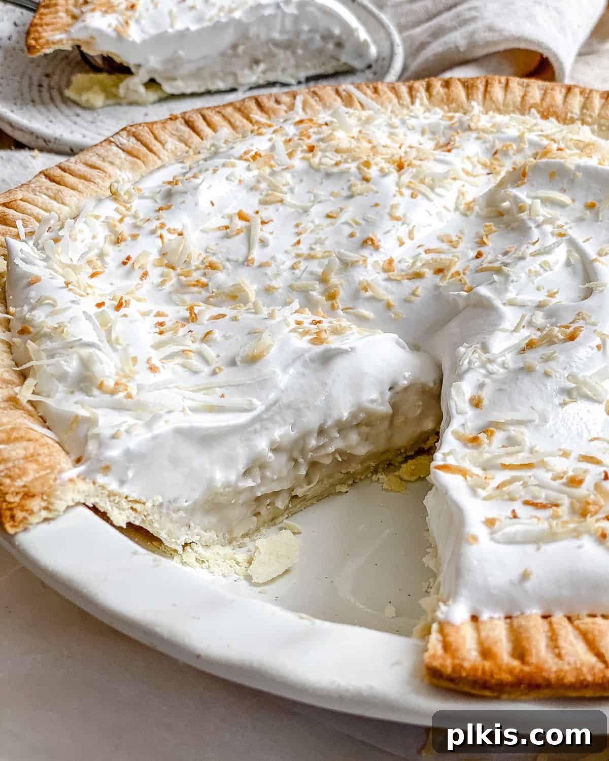 Velvety Vegan Coconut Dream Pie 2 A beautifully garnished Vegan Coconut Cream Pie, ready to be served on a white background, highlighting its creamy texture and toasted coconut flakes.