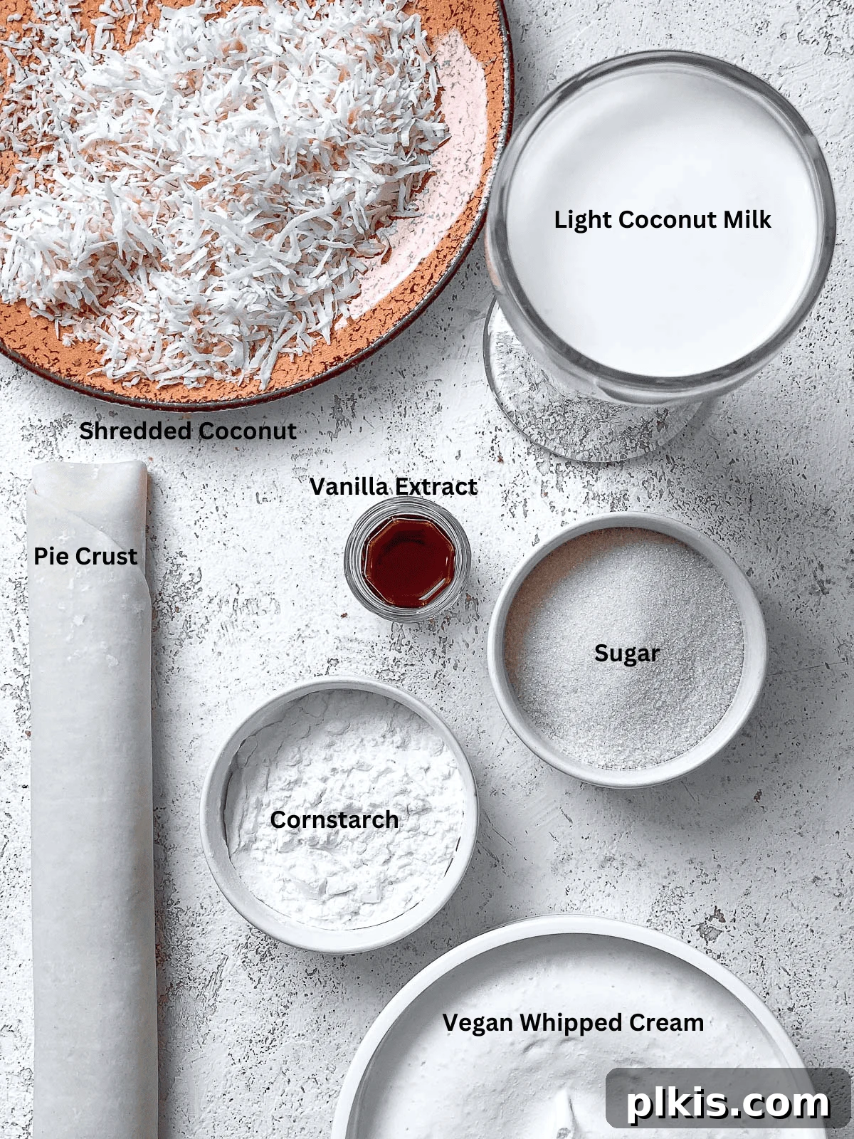 Velvety Vegan Coconut Dream Pie 3 A collection of fresh ingredients for Vegan Coconut Cream Pie laid out on a clean white surface, showcasing canned coconut milk, sugar, cornstarch, vanilla extract, and shredded coconut.