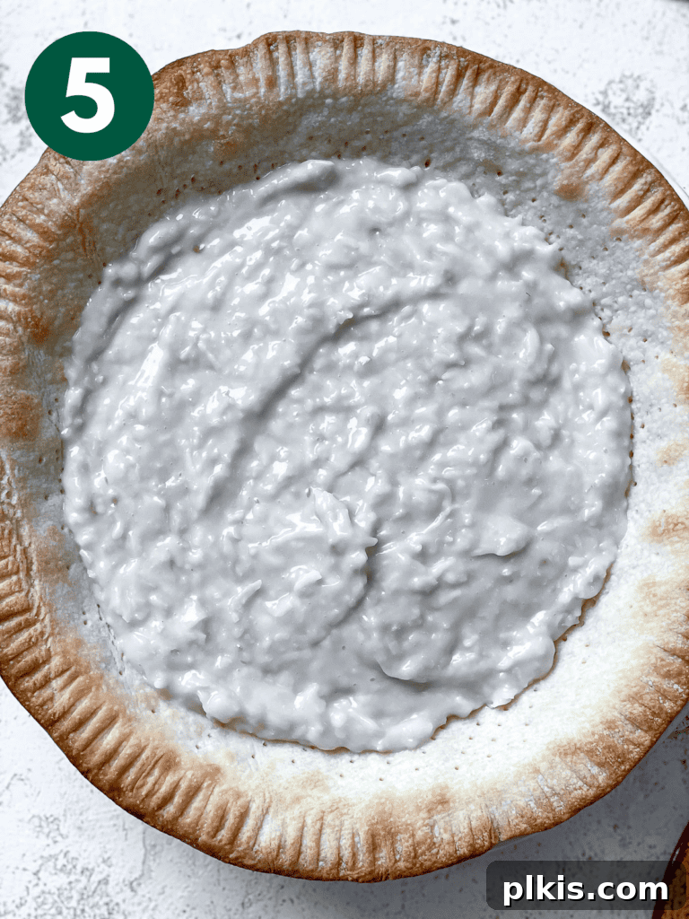 Velvety Vegan Coconut Dream Pie 8 The smooth, creamy coconut filling being poured into a pre-baked pie crust, showcasing the next step in preparing the Vegan Coconut Cream Pie.