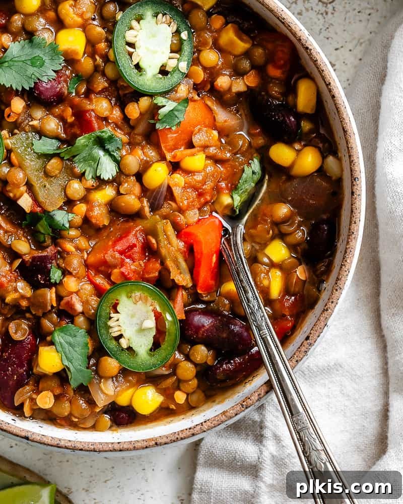 Hearty Lentil and Bean Chili 14 A steaming bowl of Lentil Bean Chili, expertly garnished with fresh cilantro and a dollop of vegan sour cream, ready to be served.