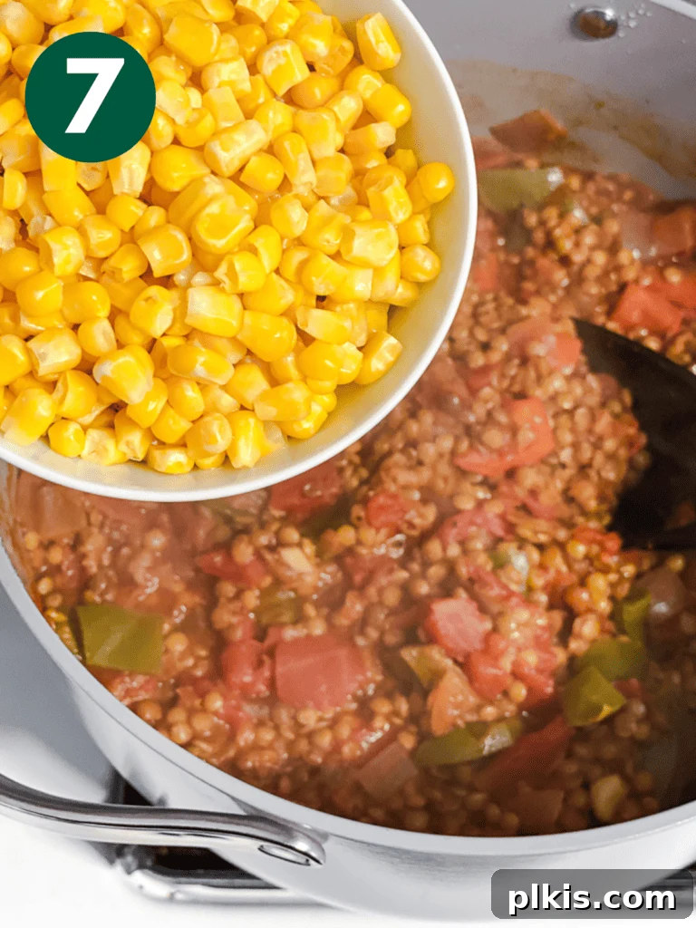 Hearty Lentil and Bean Chili 10 Golden corn kernels being added to the simmering chili, adding sweetness and texture.