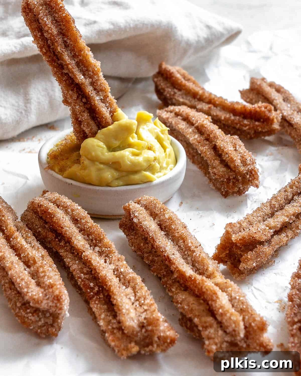 Vegan Churro Bliss 2 Dipping a golden-brown vegan churro into a small bowl of creamy vegan custard, highlighting the crispy texture and cinnamon sugar coating.