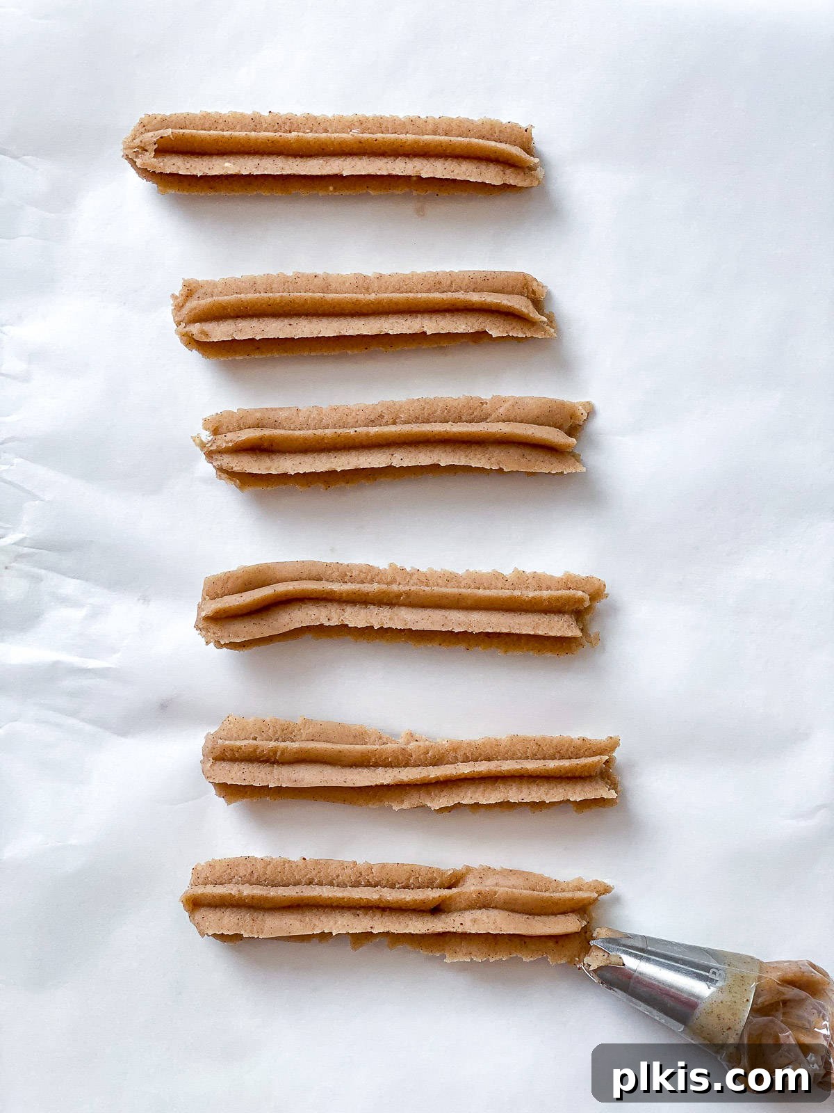 Vegan Churro Bliss 12 Vegan churro dough being piped from a piping bag with a star tip, ready to be fried.