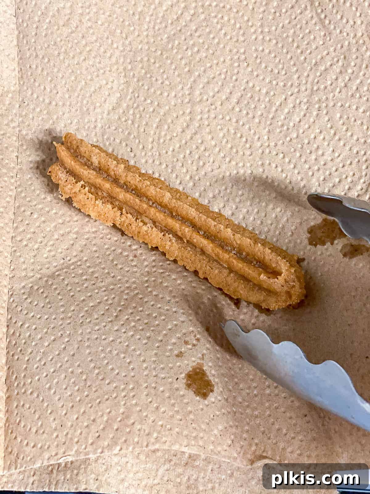 Vegan Churro Bliss 16 A freshly fried vegan churro draining on a paper towel, ready for coating.