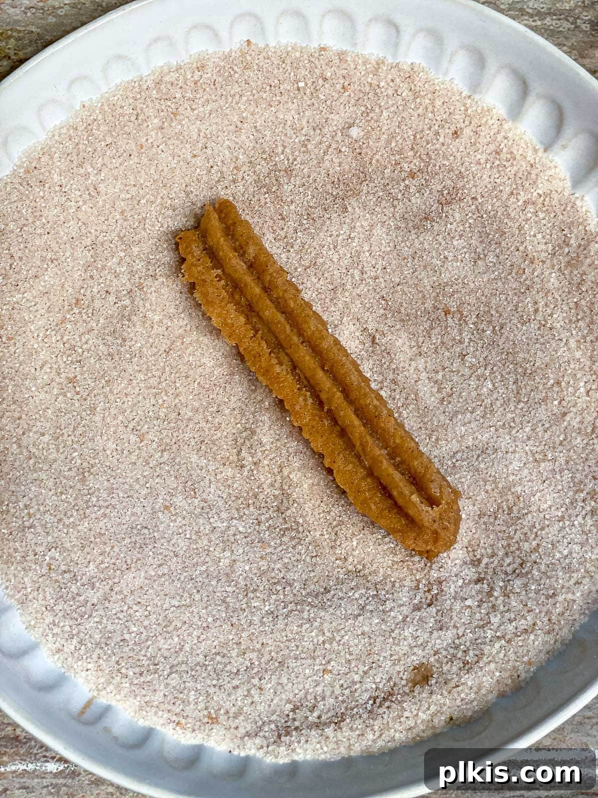 Vegan Churro Bliss 17 A vegan churro being tossed in cinnamon sugar in a white bowl, ensuring full coverage.