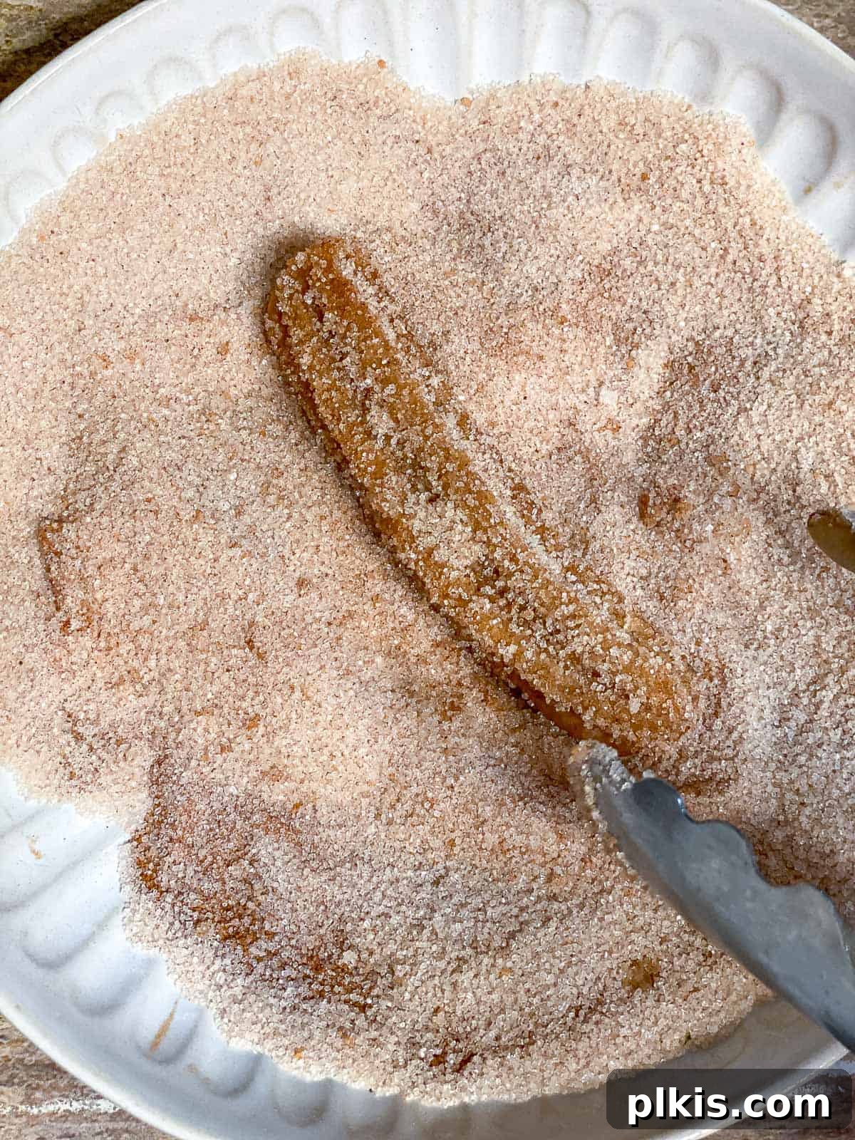 Vegan Churro Bliss 18 Close-up of a vegan churro being tossed in cinnamon sugar, showcasing the texture and coating process.