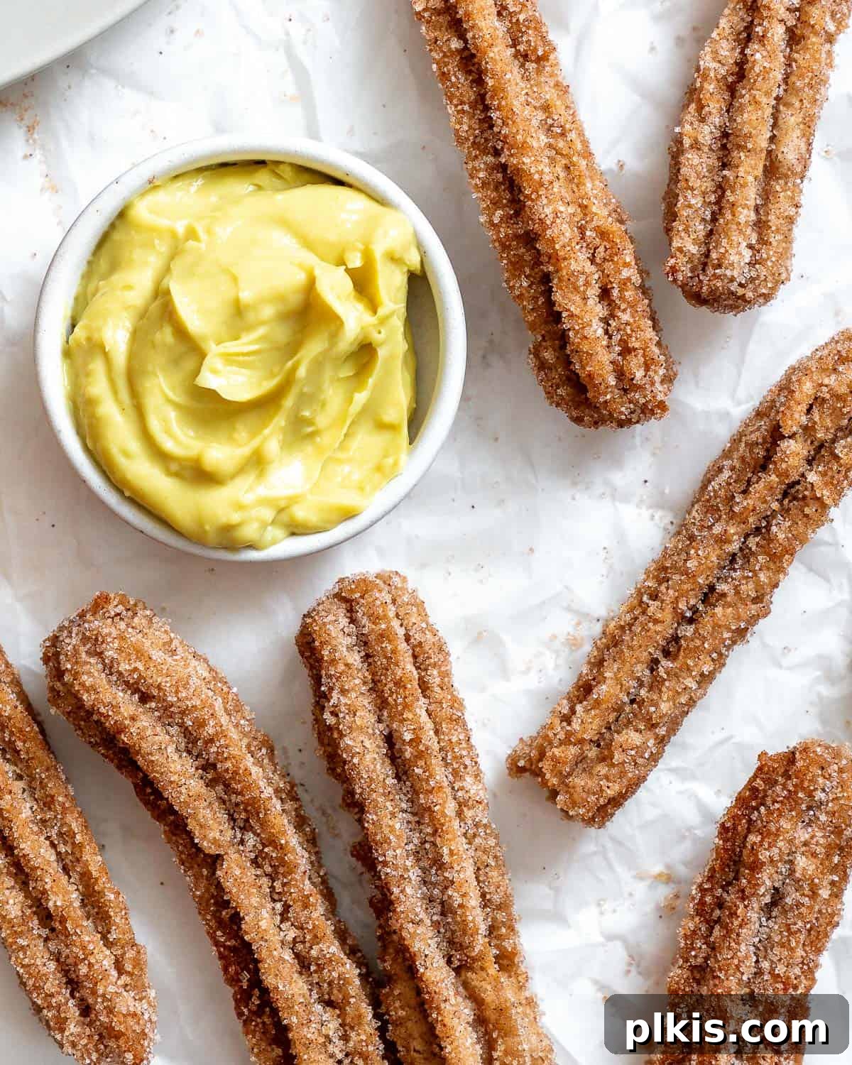 Vegan Churro Bliss 19 Close-up of perfectly cinnamon sugar-coated vegan churros arranged next to a small bowl of creamy vegan custard, ready for dipping.