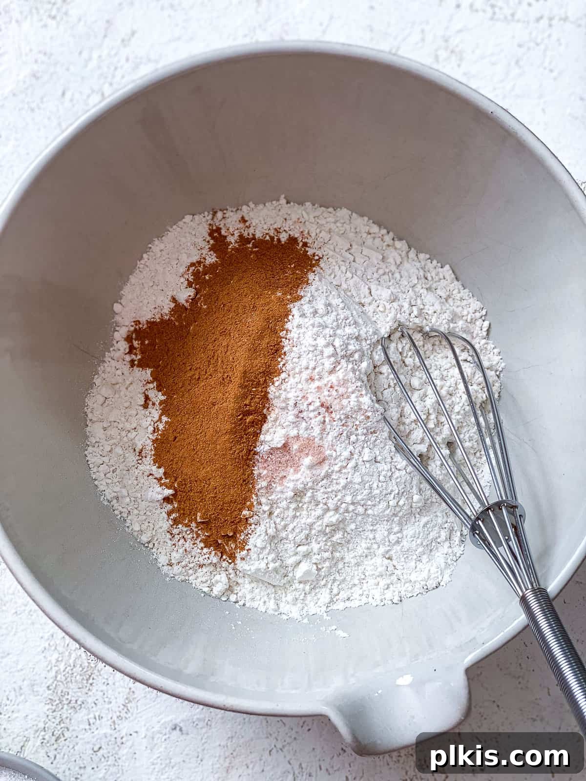 Vegan Churro Bliss 4 Whisking the dry ingredients for vegan churros in a large white bowl to ensure even distribution of spices.