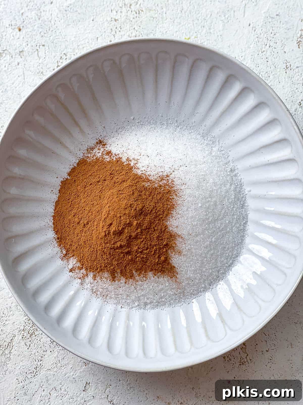 Vegan Churro Bliss 10 Cinnamon and white granulated sugar measured out in a white bowl, ready to be mixed for the churro coating.