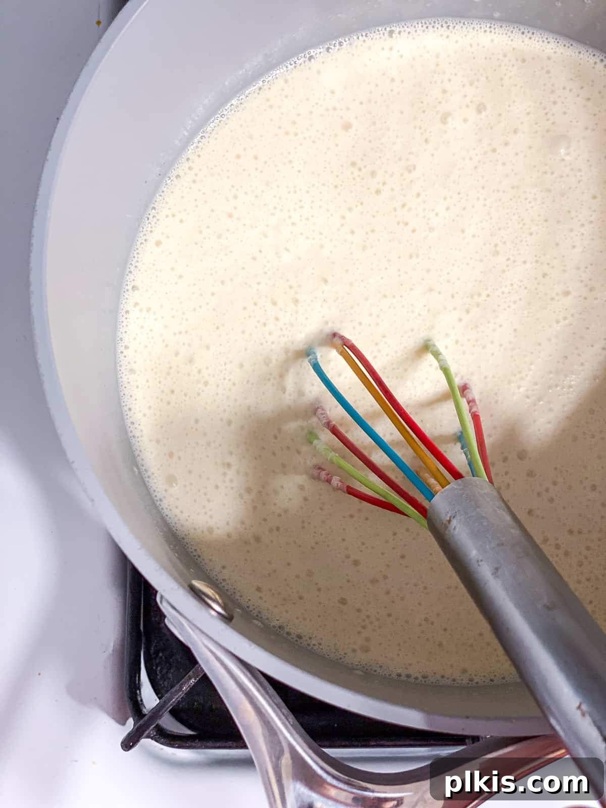 Decadent Vegan Custard 7 Whisking the uncooked vegan custard mixture gently in a grey saucepan.