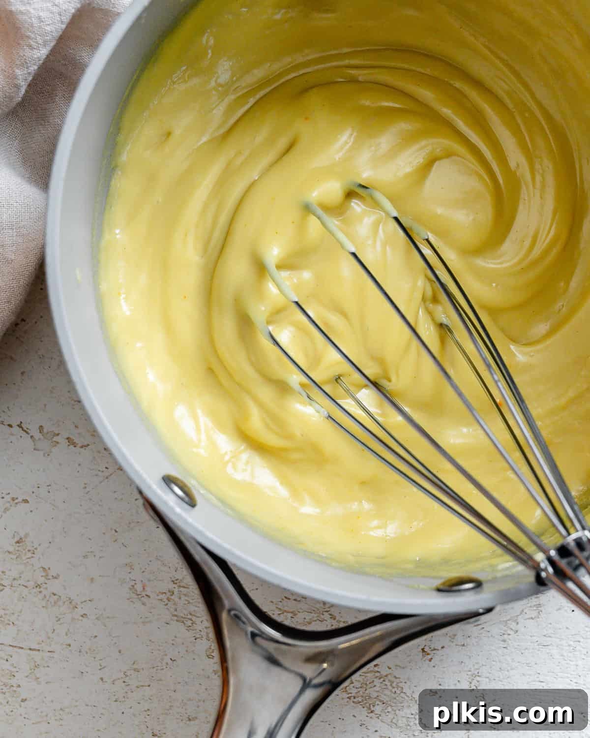 Decadent Vegan Custard 10 The process of whisking vegan custard in a grey saucepan, highlighting the smooth texture.