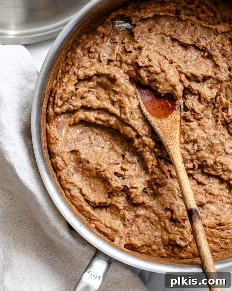 Creamy Plant-Powered Refried Beans 14 A pot of finished Vegan Refried Beans, garnished with fresh cilantro, showcasing its rich and creamy texture