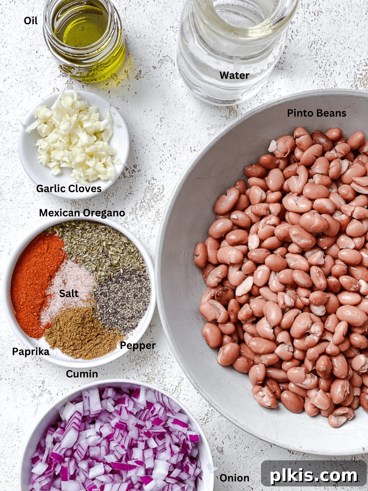 Creamy Plant-Powered Refried Beans 3 A vibrant selection of ingredients laid out for making Vegan Refried Beans including canned pinto beans, fresh onions, garlic, olive oil, and various spices.