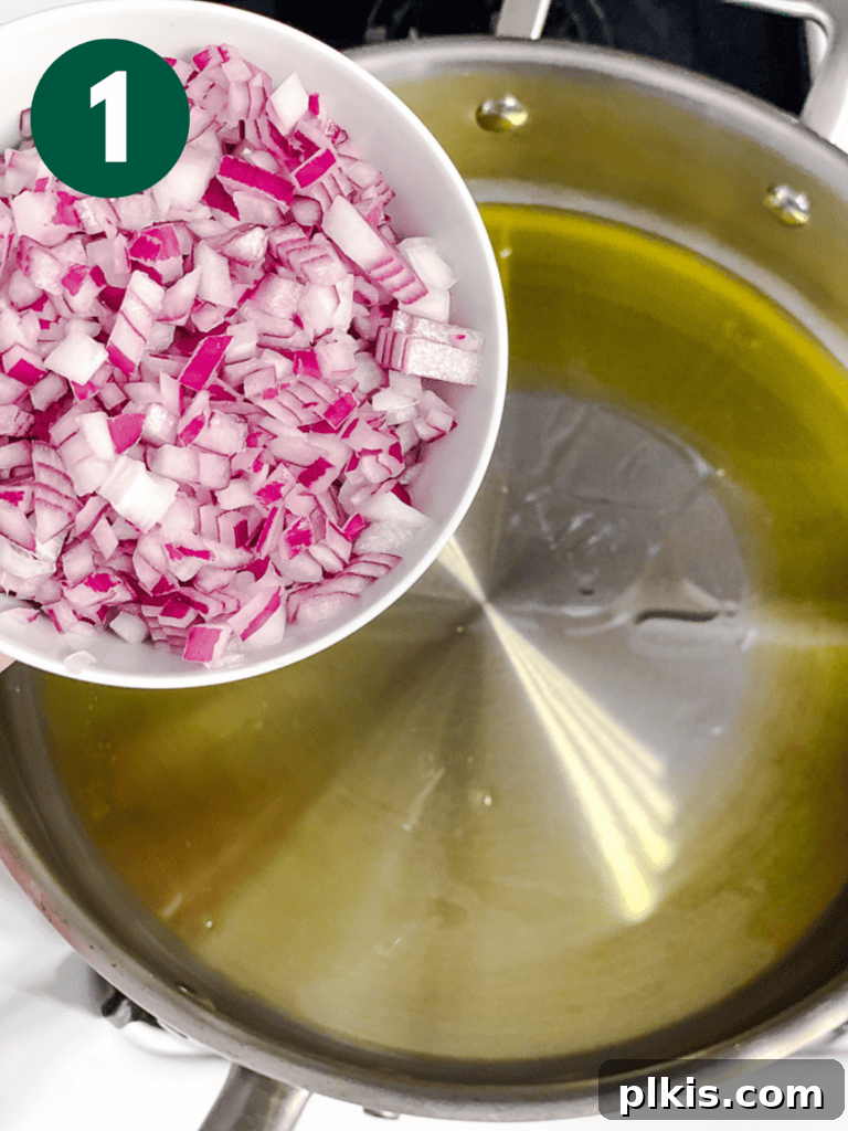 Creamy Plant-Powered Refried Beans 4 Process shot of adding finely diced onions to a hot pan with olive oil