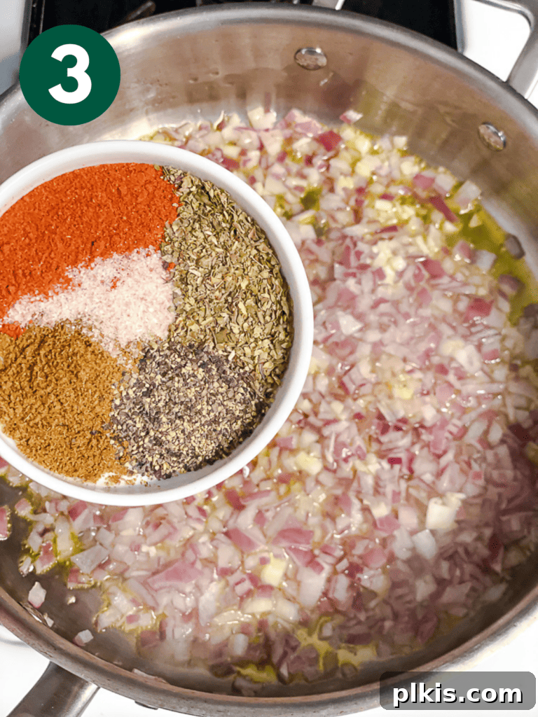 Creamy Plant-Powered Refried Beans 6 Process shot of adding cumin, oregano, and paprika to the sautéed aromatics