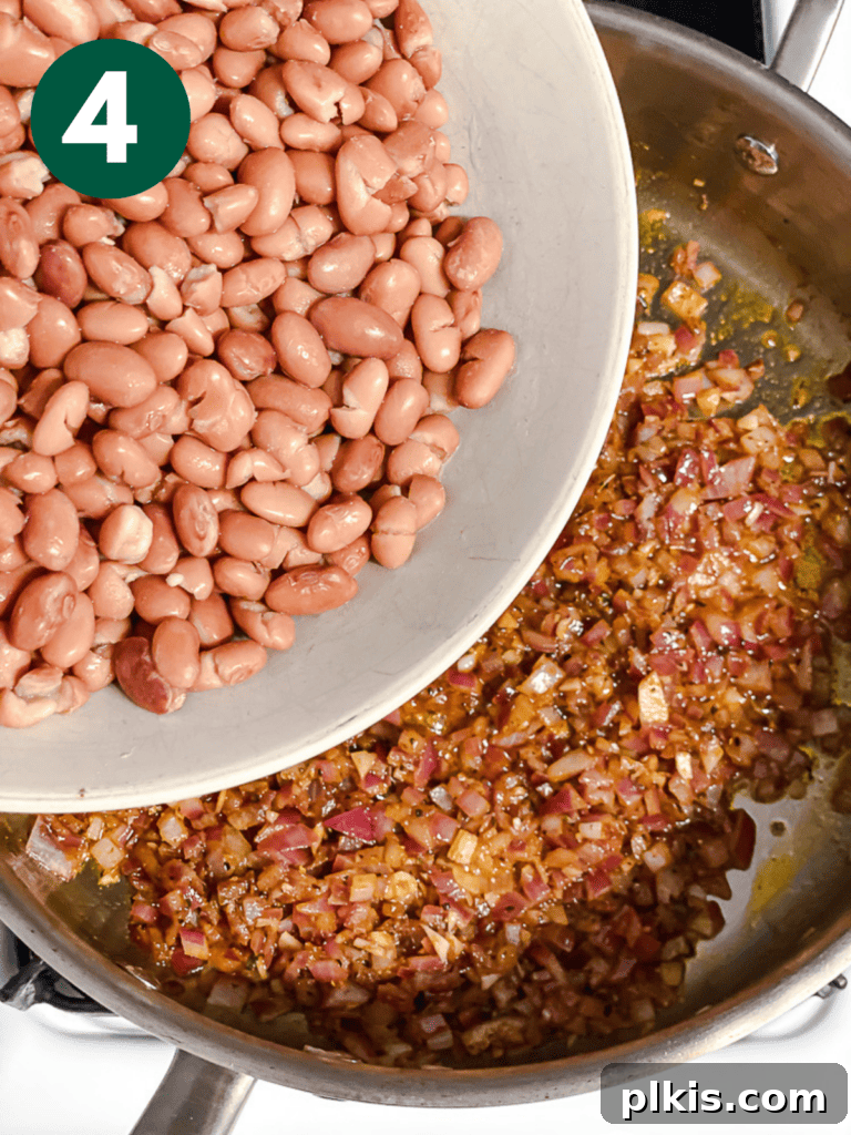 Creamy Plant-Powered Refried Beans 7 Process shot of adding pinto beans to the pan with spices and aromatics