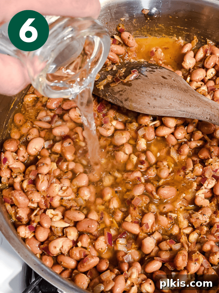 Creamy Plant-Powered Refried Beans 9 Process shot of adding water to the seasoned beans in the pot