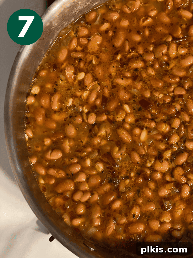 Creamy Plant-Powered Refried Beans 10 Process shot of the beans simmering gently in a lidded pot on the stove