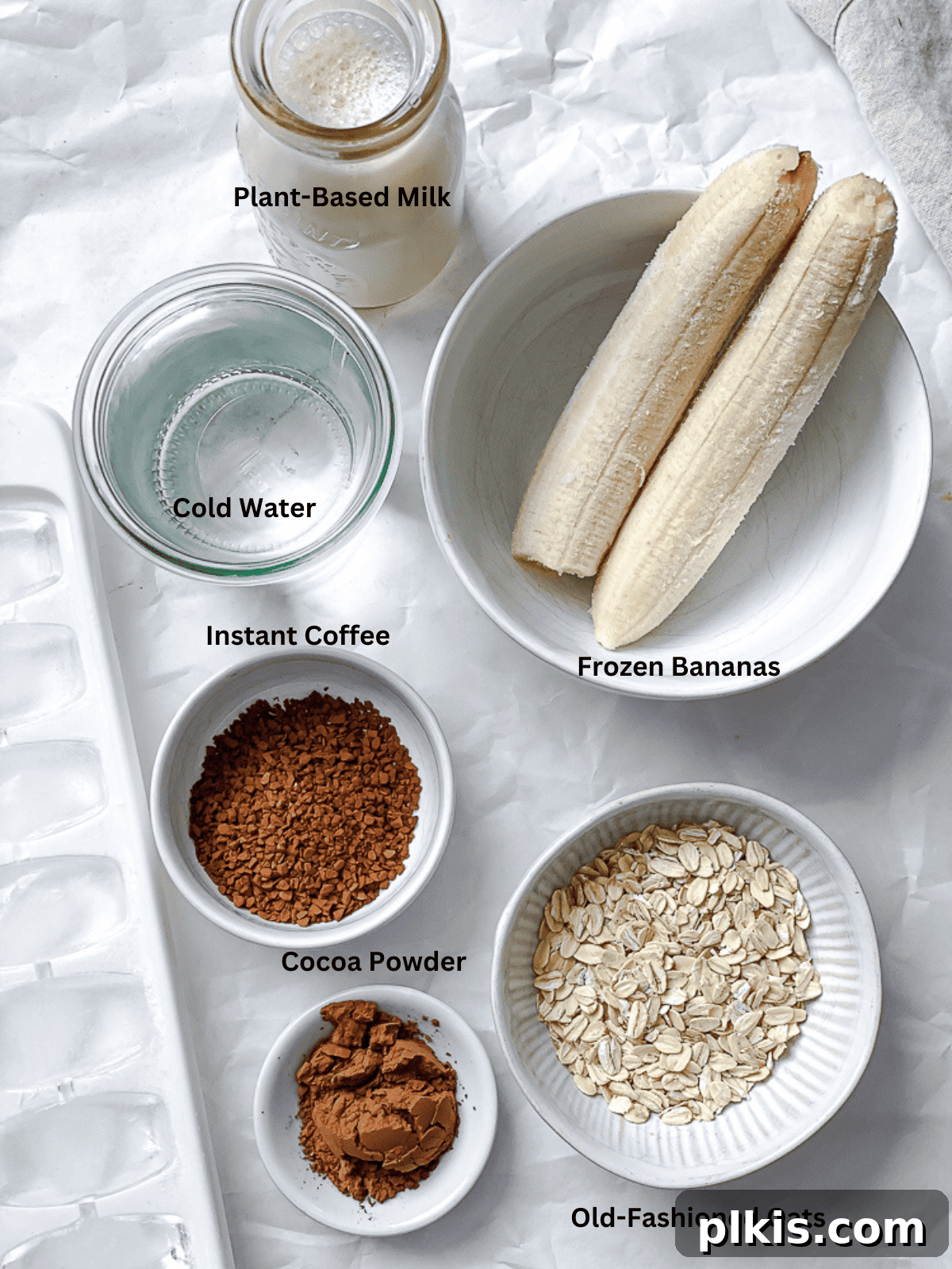 Coffee Kick Smoothie 3 A curated selection of fresh ingredients including coffee, plant milk, bananas, oats, cocoa, and sweetener, neatly arranged for a coffee smoothie.