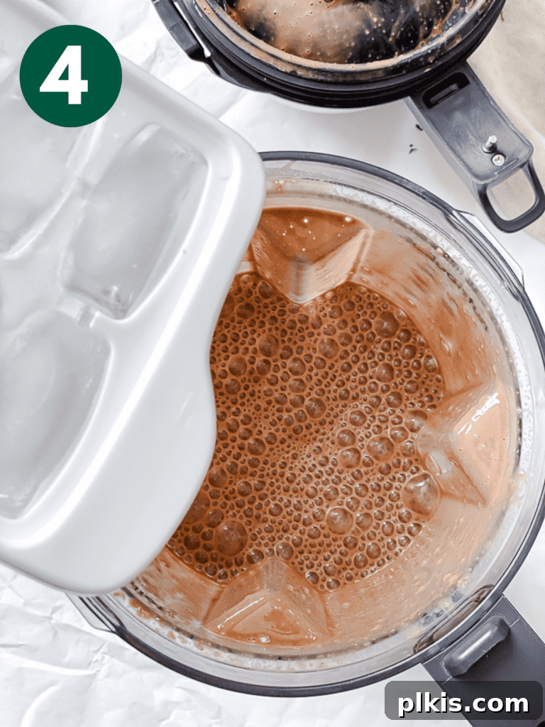 Coffee Kick Smoothie 7 Ice cubes being added to the blended coffee smoothie mixture in the blender, preparing it for the final pulse for a perfectly chilled consistency.