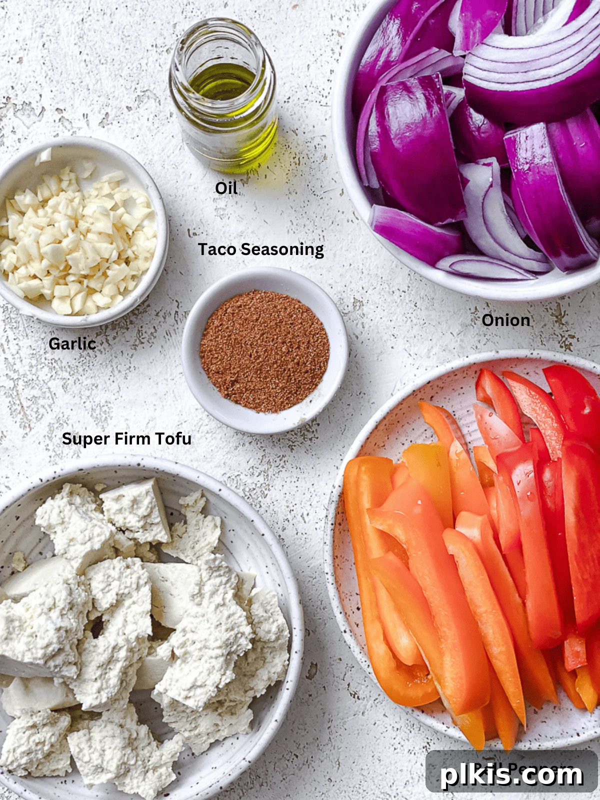 Zesty Tofu Fajita Feast 3 Individual white bowls showcasing the fresh ingredients needed for sheet pan tofu fajitas, including bell peppers, onions, tofu, garlic, taco seasoning, and oil.