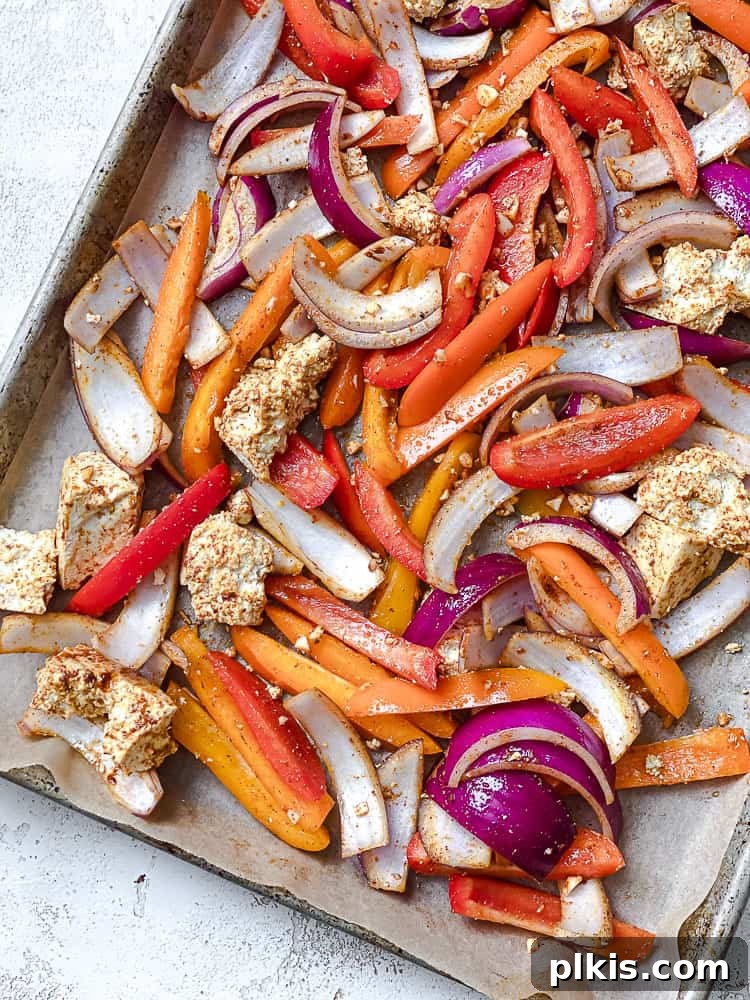 Zesty Tofu Fajita Feast 5 Process shot showing the same bell peppers, onions, and tofu after being baked, appearing tender and lightly charred on the baking tray.