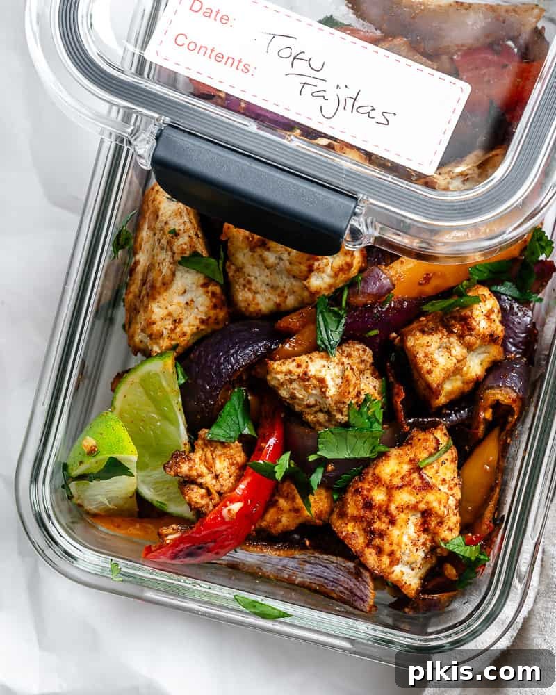 Zesty Tofu Fajita Feast 7 Cooked bell peppers, onions, and tofu in a clear glass storage container, highlighting meal prep convenience.