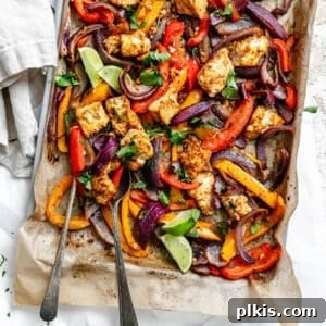 roasted taco-seasoned tofu chunks, onion, and bell peppers on a parchment-lined sheet pan.