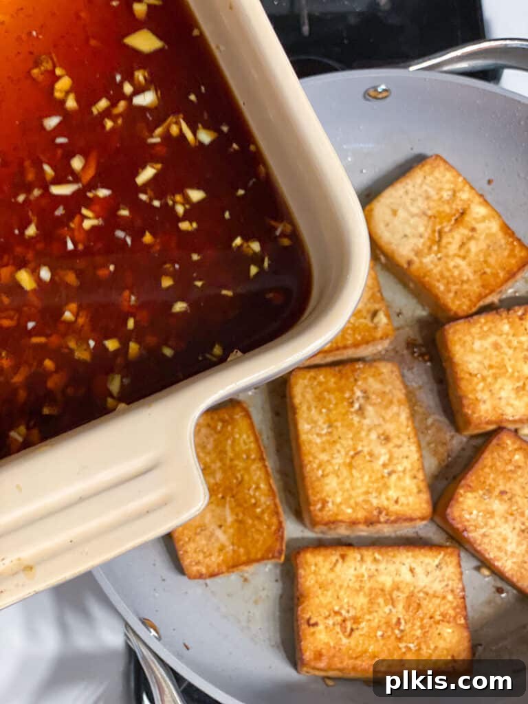 Effortless Tofu Adobo 13 Process shot showing the remaining marinade being added to the browned tofu in a skillet.