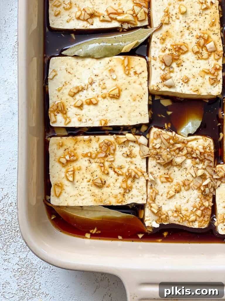 Effortless Tofu Adobo 10 Process shot showing tofu fully immersed in the marinade in a container.