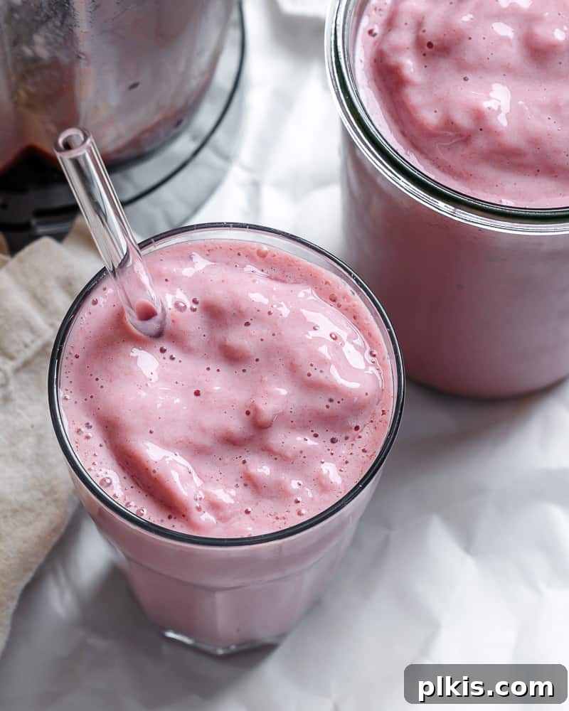 Two glasses of vibrant Strawberry and Pineapple Smoothie garnished with fresh berries and mint