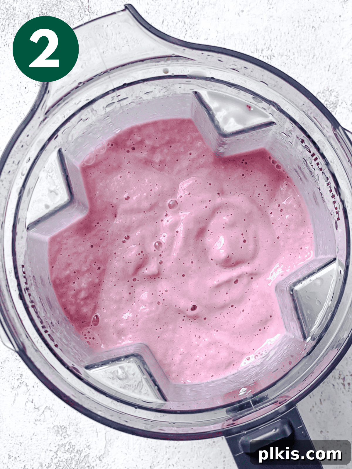 Process shot showing the blended, smooth Strawberry and Pineapple Smoothie swirling in a blender