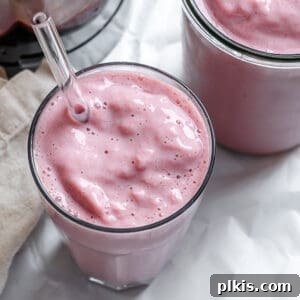 Two glasses of completed Strawberry and Pineapple Smoothie on a white surface