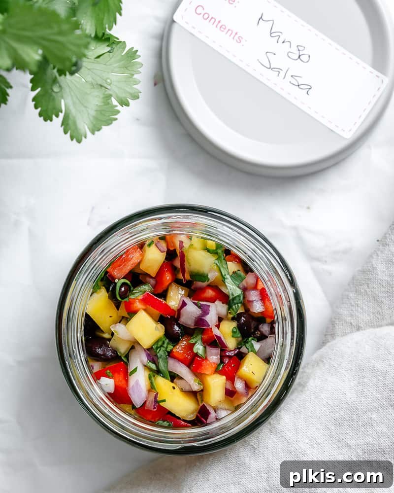 Golden Mango Burst 8 mango salsa in a glass jar next to a white lid labeled "mango salsa".