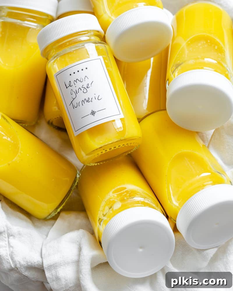 Golden Glow Immunity Booster 2 Several containers of homemade Lemon Ginger Turmeric Shots, showcasing their vibrant color, arranged neatly on a pristine white surface, ready for consumption and a healthy lifestyle.