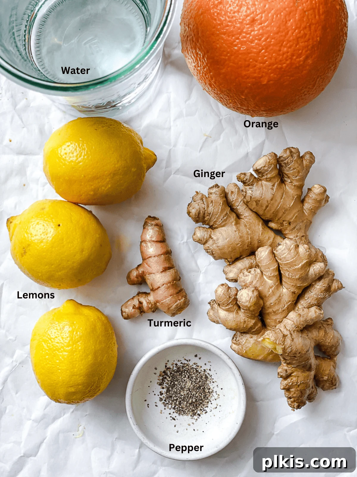 Golden Glow Immunity Booster 3 Fresh ingredients for Lemon Ginger Turmeric Shots, including vibrant lemons, oranges, ginger root, and turmeric root, neatly arranged on a white surface, ready for preparation.