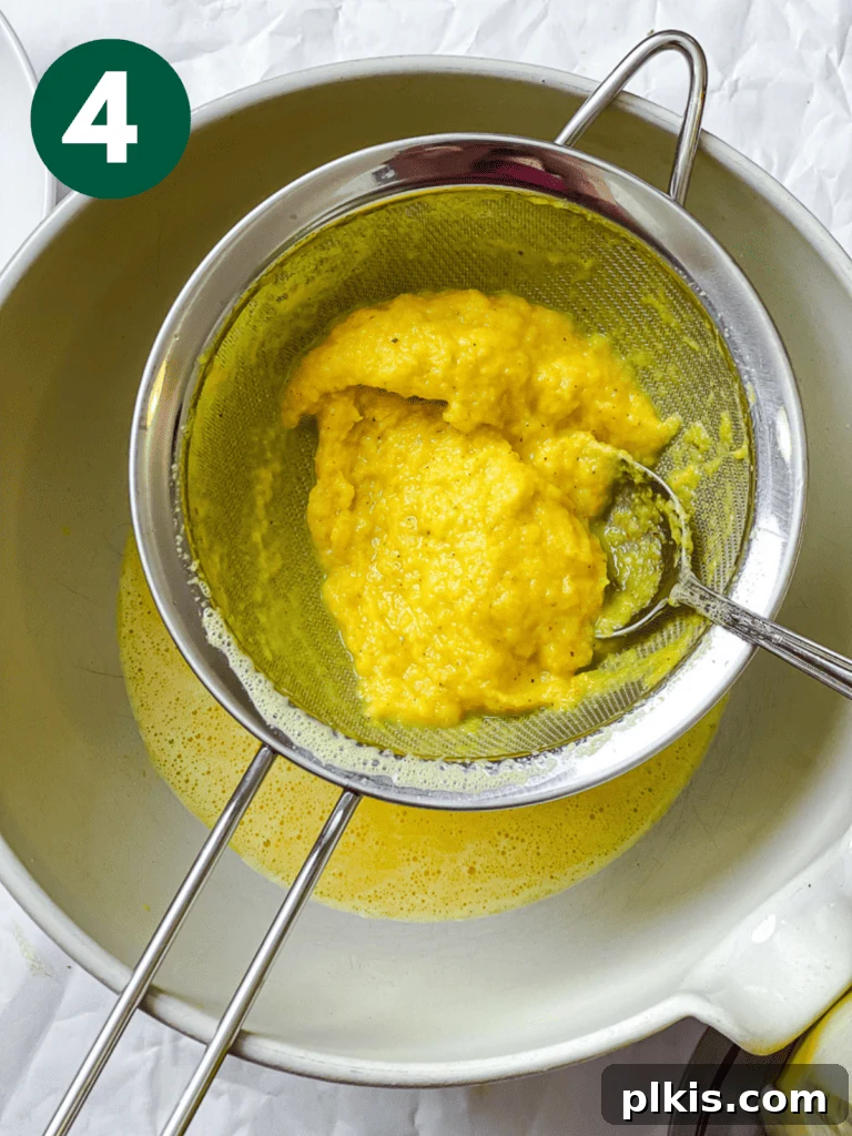 Golden Glow Immunity Booster 7 Process shot revealing the leftover strained pulp in a fine-mesh strainer, illustrating the separation of fibrous material from the liquid wellness shot.