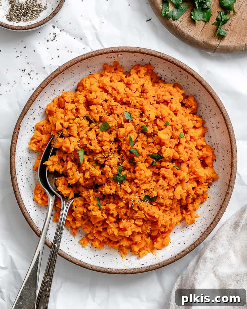 Simple Sweet Potato Rice 2 Completed Easy Riced Sweet Potato plated on a white surface, garnished with fresh herbs.
