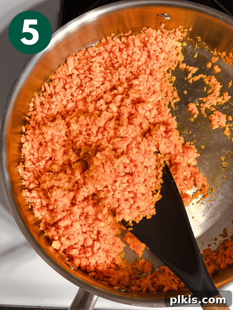 Simple Sweet Potato Rice 8 Process shot showing cooked riced sweet potato being stirred in the pan.