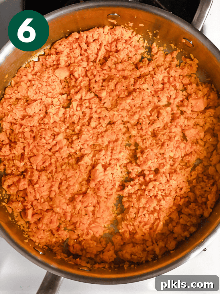 Simple Sweet Potato Rice 9 Process shot showing the final stages of riced sweet potato cooking in a pan, fully browned and tender.
