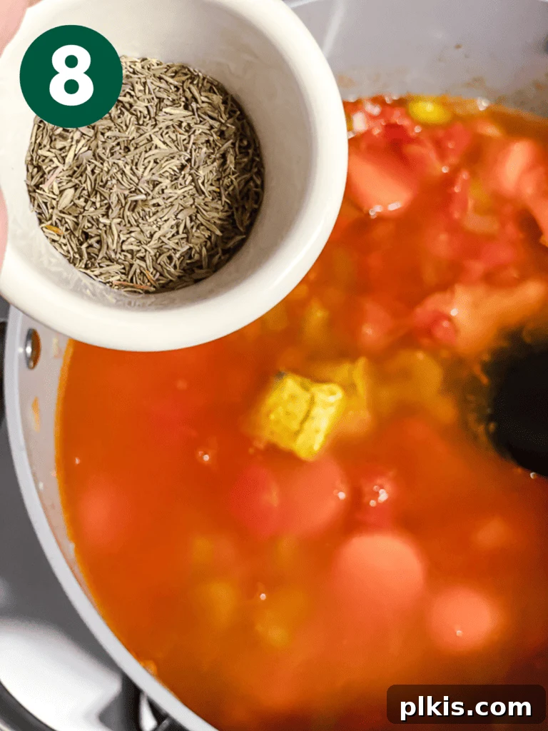 Hearty Vegan Cabbage Soup: Stove Top, Instant Pot, and Slow Cooker 11 Process shot: Adding a generous sprinkle of dried thyme to the simmering soup for aromatic flavor.