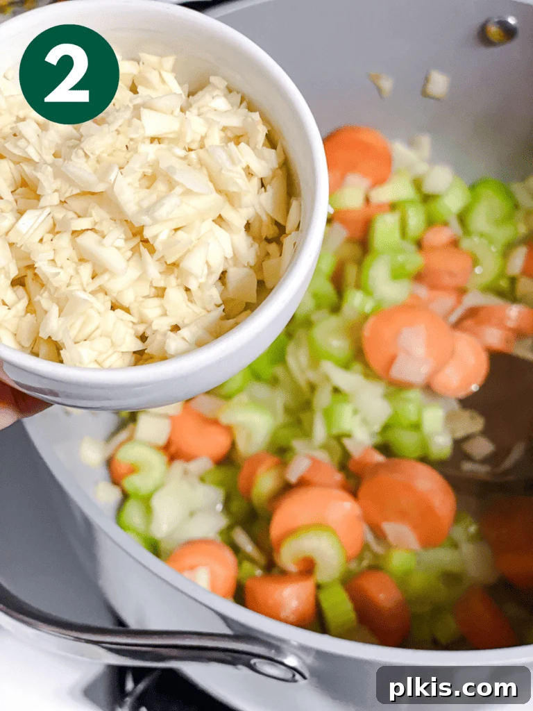Hearty Vegan Cabbage Soup: Stove Top, Instant Pot, and Slow Cooker 5 Process shot: Minced garlic being added to the sautéed vegetables in the pan, filling the kitchen with an aromatic fragrance.