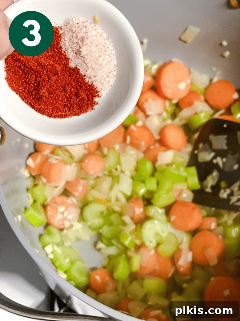 Hearty Vegan Cabbage Soup: Stove Top, Instant Pot, and Slow Cooker 6 Process shot: Paprika and other spices being sprinkled over the vegetables in the pan, ready to be stirred in and release their flavors.