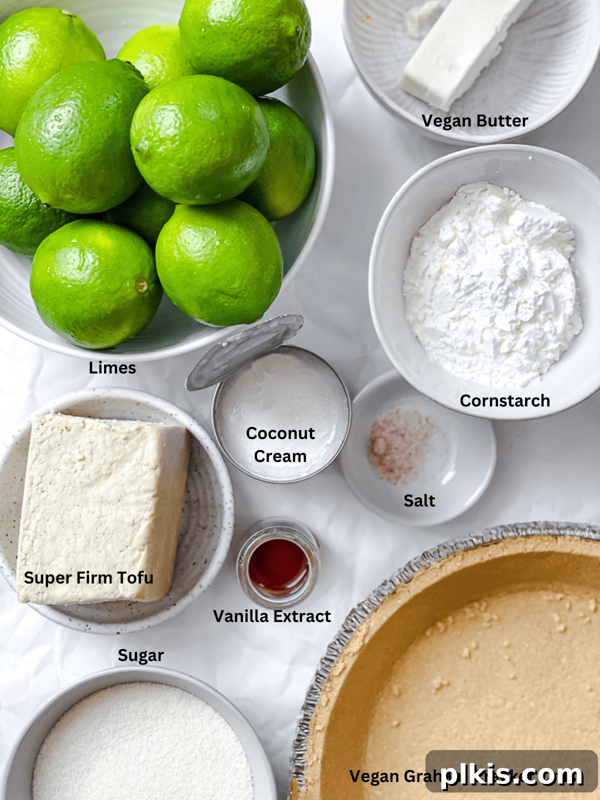 Effortless Zesty Vegan Key Lime Pie 3 Ingredients for Easy Vegan Key Lime Pie laid out, including limes, coconut cream, sugar, and a pie crust.