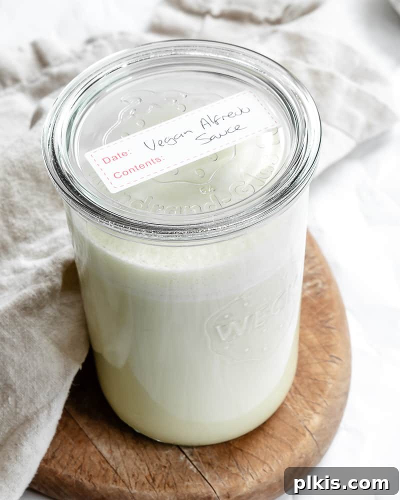 Plant-Based Alfredo Bliss 7 a glass jar filled with vegan alfredo sauce with a label on top.
